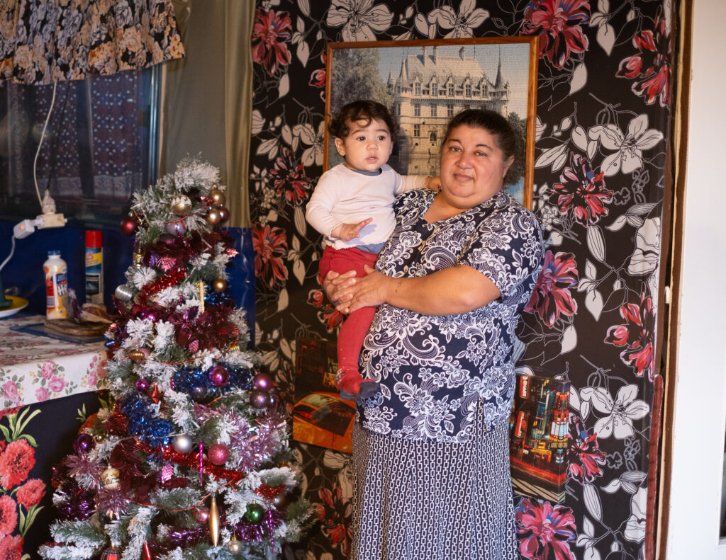 Une femme tient un enfant dans ses bras à côté d'un sapin de noël