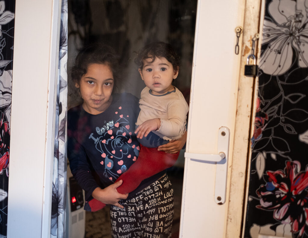 Une femme tient un enfant dans ses bras dans l'entrebâillement d'une porte