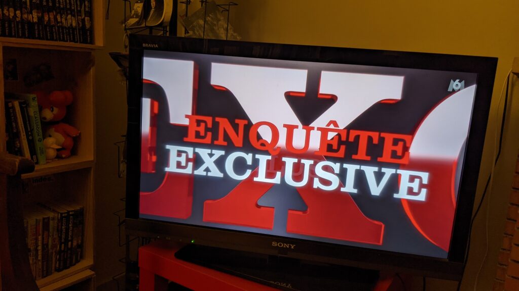 On voit à l'image l'écran d'une télévision allumée sur le générique de l'émission Enquête exclusive