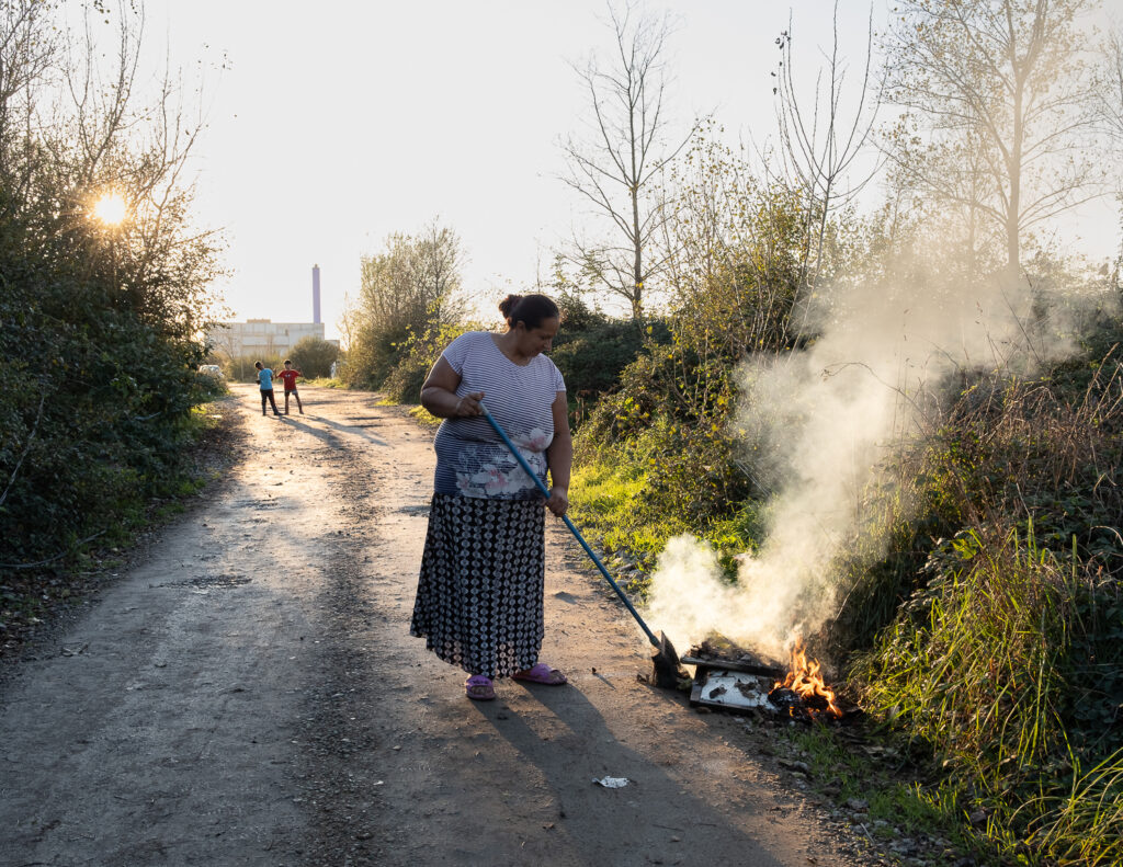 Une femme sur un chemin balaie et brule des ordures