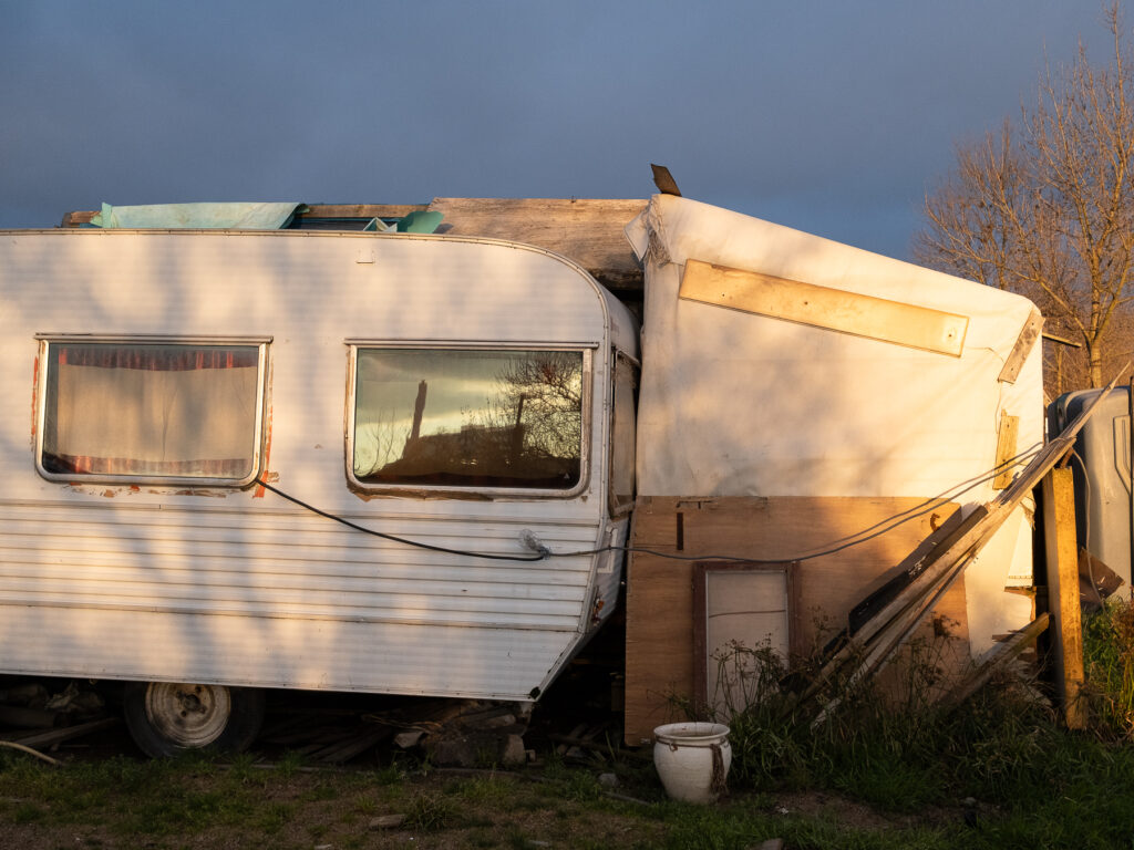 une caravane renforcée par des bâches et des planches