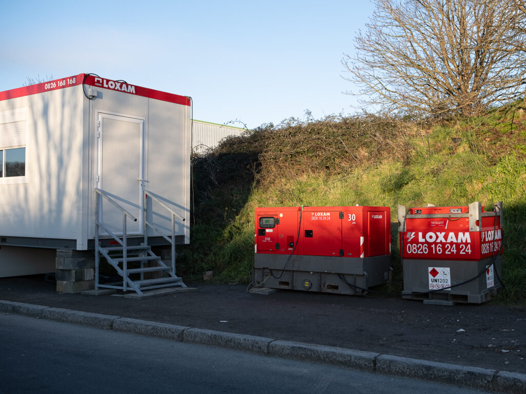 un pre-fabriqué blanc a été installé sur le site à côté d'un bloc technique rouge juste en bordure de talus